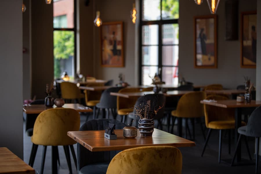 Gedekte tafels met okergele stoelen in de brasserie